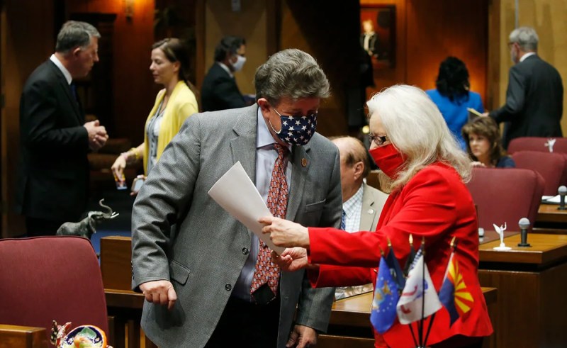man and woman speak to each other in Arizona House with masks on