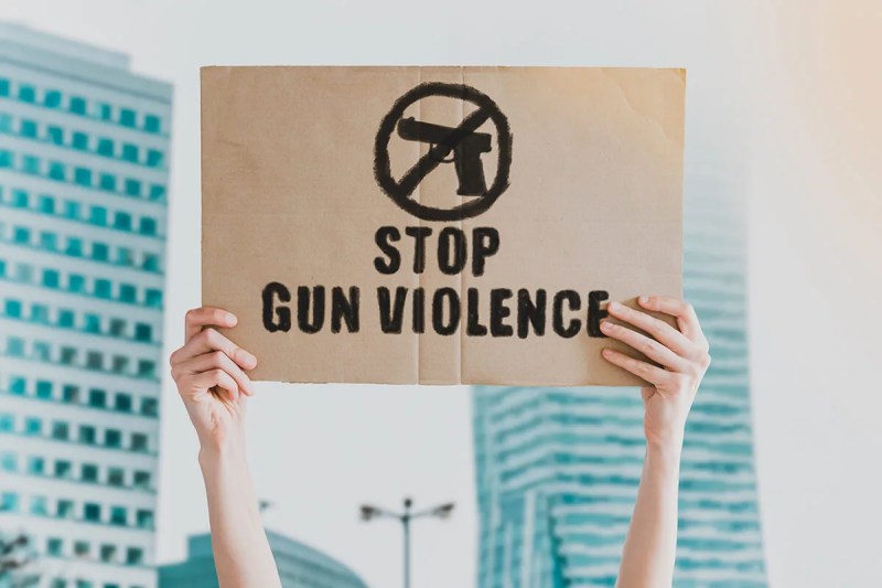 person holding sign that says "stop gun violence"