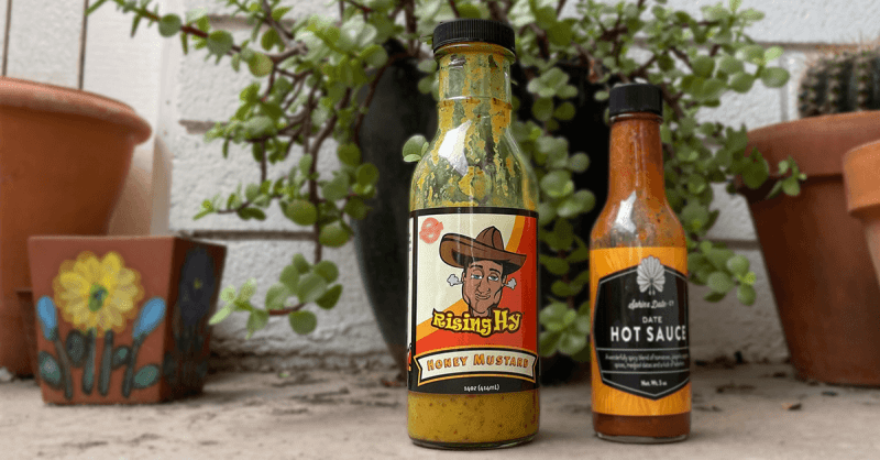 two hot sauce bottles positioned in front of plants