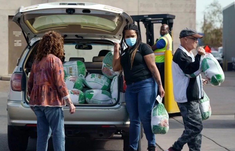 people unloading wrapped raw turkeys from the trunk of a car