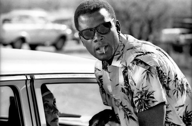 sidney poitier wearing sunglasses leaning toward a car