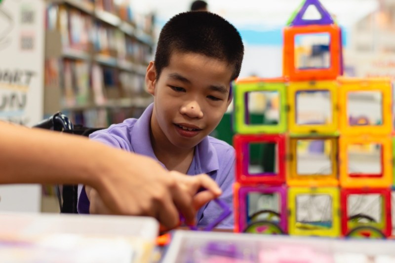 Disabled child on wheelchair is interested in skills development toys in Books and toys fair,Special children's lifestyle,Life in the education age of special need kids,Happy disability kid concept.