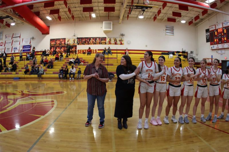 Karen Self on basketball court with players beside her