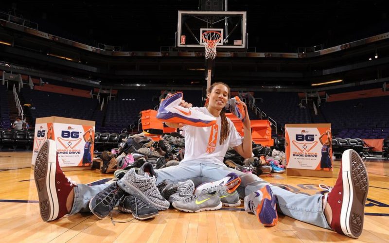Brittney Griner sitting on basketball court surrounded by shoes