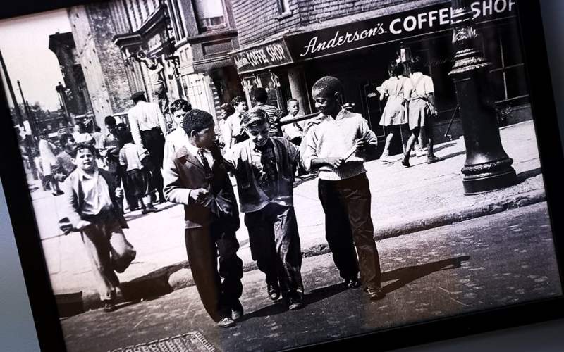 A photograph from the ‘Black Folk Photography’ exhibit depicts Black and white children walking together across a street in New York City during the 1930s.
