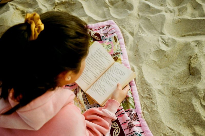 girl reading a book in sand