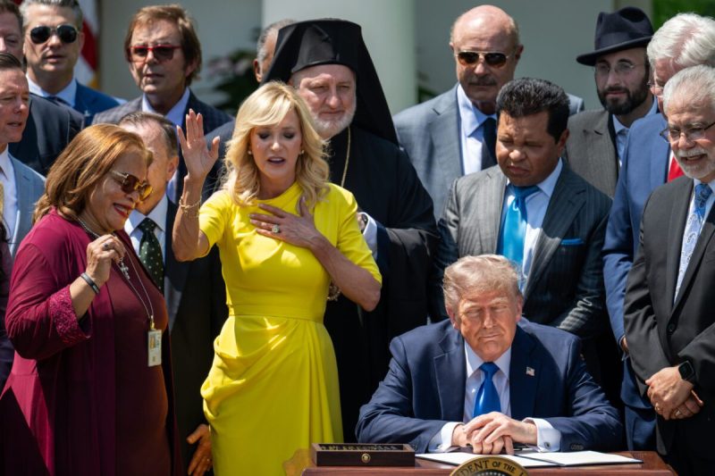 people praying standing around President Trump