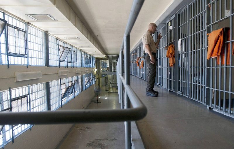 a guard looking into a cell in a prison