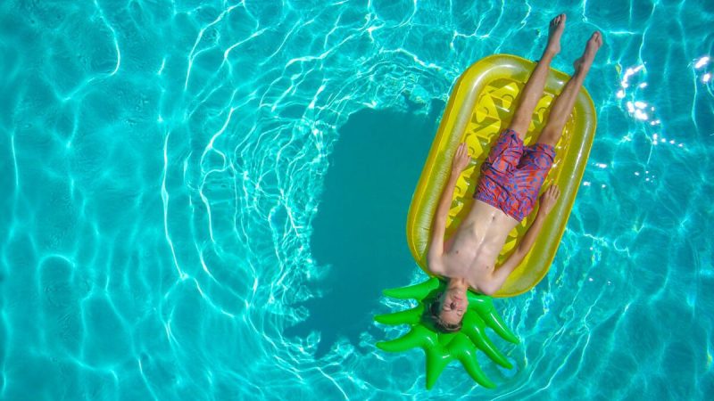 person floating in a pool on a pineapple shaped float