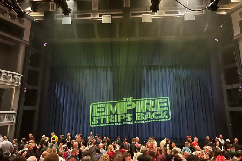 a stage with "The Empire Strips Back" projected onto the curtain