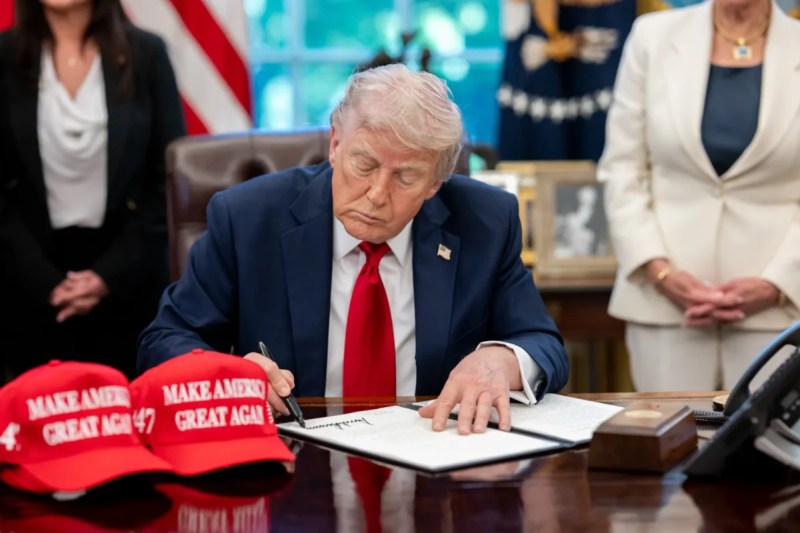 Trump signing a paper at a desk