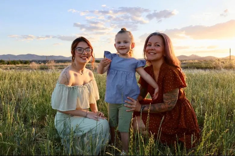 family photo of two daughters and mom at sunset