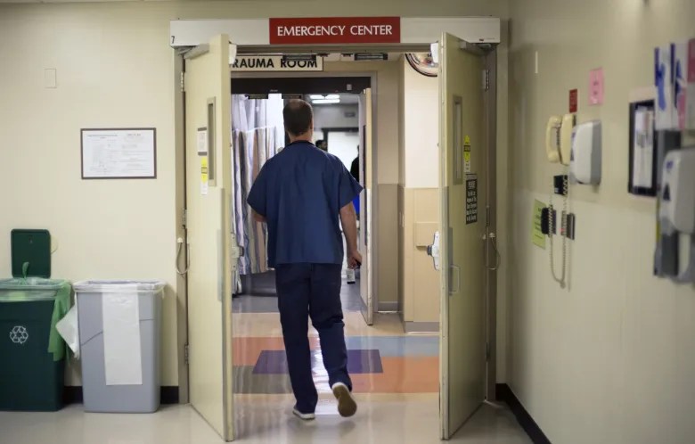 a worker walking under the emergency room door in a hospital