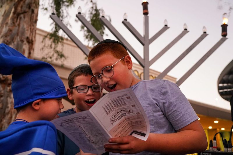 children singing Hanukkah songs from a booklet