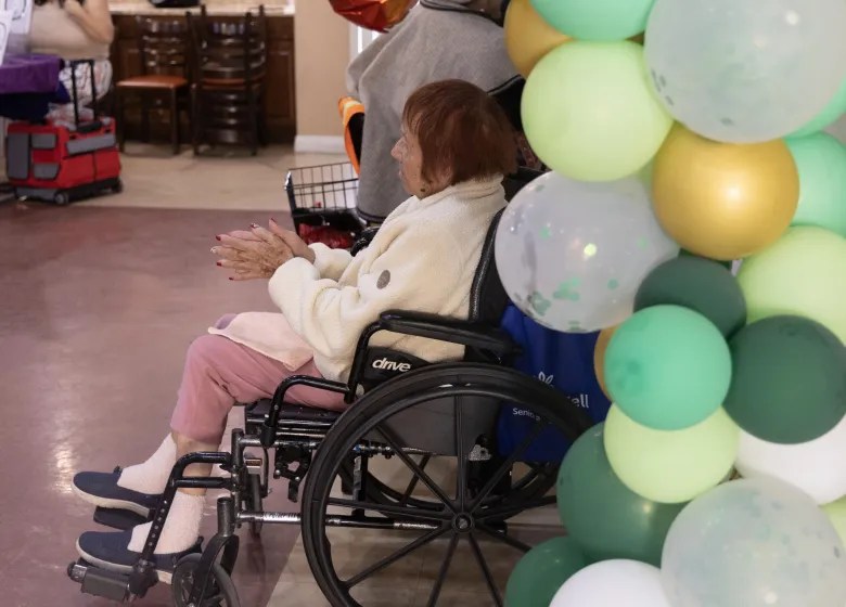 elderly woman in wheelchair next to a display of balloons