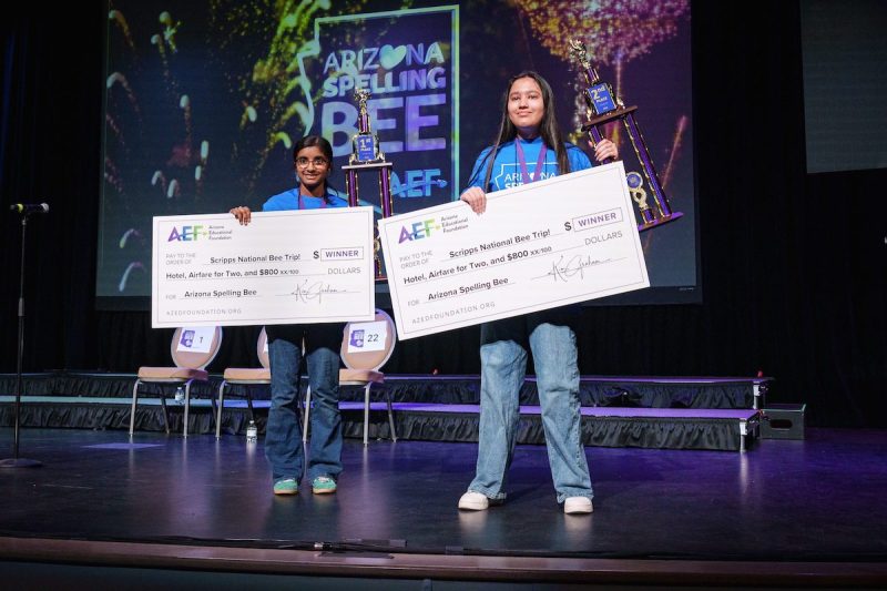 two young girls posing on a stage with big checks