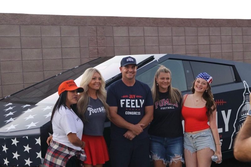 group of people posing in front of a Cybertruck