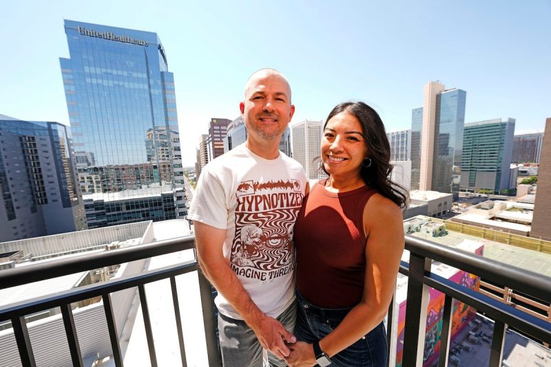 man and woman standing on balcony in high rise overlooking cityscape