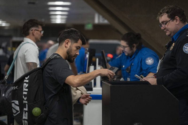 TSA agent checking a man's ID at a security checkpoint in the airport