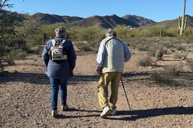 two elderly people walking along a hiking trail in the desert