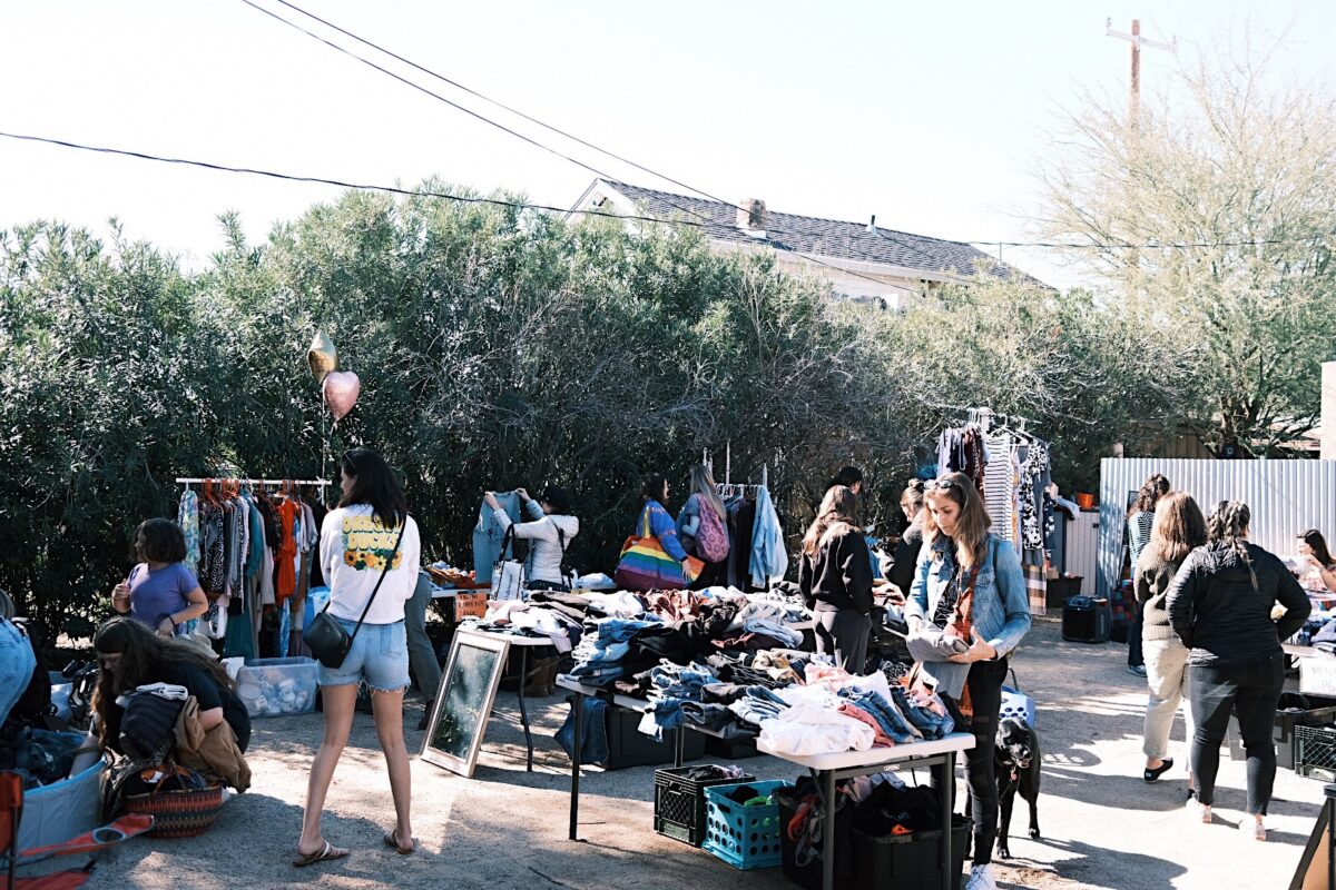 tables of clothing sorted by size with people looking through the items