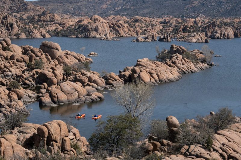aerial view of a lake with rock formations, and kayakers moving through the water